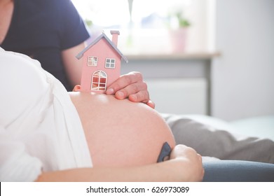 Close Up Of Pregnant Belly With Small Wooden House Concept, Of New Home And Family