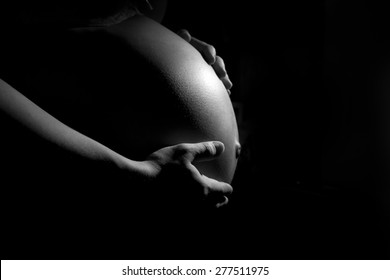 Close Up Of Pregnant Woman Belly On The Dark