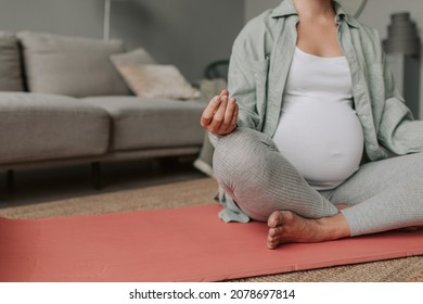 Close Up Pregnant Woman Deep Breathing Doing Yoga In Lotus Pose On Mat At Home.