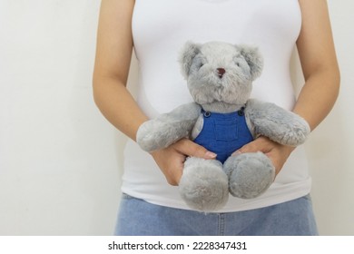 Close up pregnant woman holding teddy bear. Concept of pregnancy, Asian Young mother waiting of the baby.