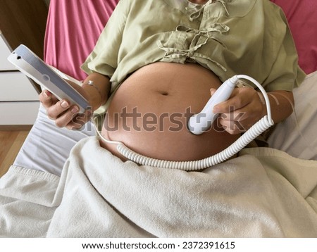 close up pregnant woman patient using fetal droppler device to listening baby heartbeat on a bed in hospital