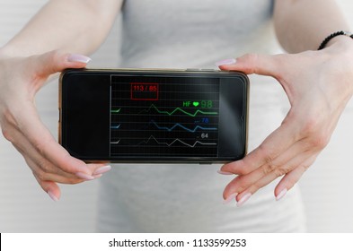 Close Up Of Pregnant Woman Showing Ecg Of A Baby On A Smart Phone.