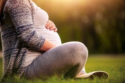 Close Up Of A Pregnant Woman Sitting And Holding Her Belly.
