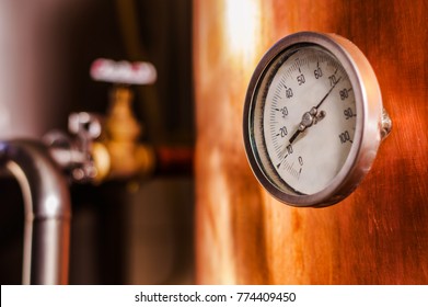 Close up of a pressure gauge inside of a modern beer plant brewery with vessels, tubs and pipes made of stainless steel, in a beer plant in Quito