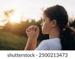 Close up of pretty little girl kid in park praying alone during warm sunset, child prayer, World Day of Prayer, international day of prayer, trust concept, hope, gratitude, thankful, trust