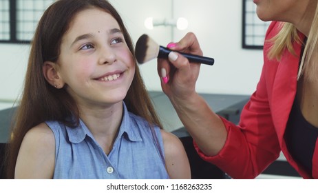 Close Up Of A Pretty Little Girl Smiling While Her Mom Applying Makeup On Her Face