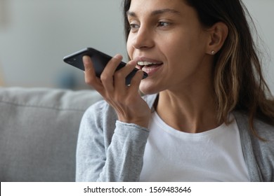 Close up of pretty woman holding in hand smart phone talking with digital assistant or friend distantly uses easy voice messaging, concept of modern ai technology, voice recognition, online translator - Powered by Shutterstock