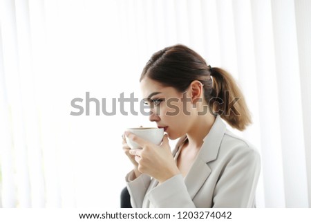 Close up Pretty Young Office Asian Woman Smelling the Aroma of her Coffee Drink in a Red Cup with Eyes Closed.