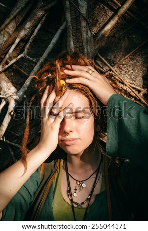 Close up Pretty Young Woman with Dreadlocks Blond Hair Covering her One Eye While Lying on Sticks.