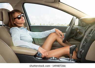 Close up of pretty young woman with sunglasses relaxing in the brand new luxury car