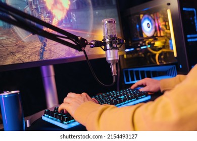 Close Up Of Pro Gamer's Hands Laying On Gaming Keyboard While He Streaming His Online Video Game Passing On Powerful PC At Home. Professional Setup For Cyber Sport Tournaments And Gaming. Neon Color