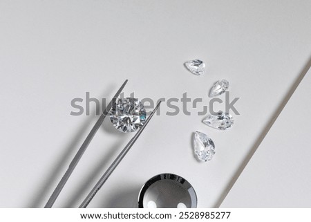 Close up of the process of evaluating natural diamonds using jeweller's tools. Workshop shows diamonds of various cuts and sizes.