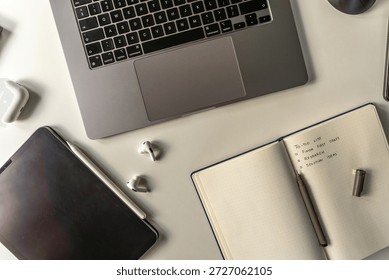 Close up of productivity and remote work concept with laptop, tablet, phone, notebook, accessories, on a clean, light workspace.