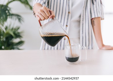 Close up professional barista hand pouring freshly brewed drip coffee in a glass mug. Preparing coffee alternative method. - Powered by Shutterstock