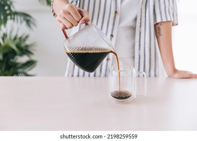 Close up professional barista hand pouring freshly brewed drip coffee in a glass mug. Preparing coffee alternative method. - Powered by Shutterstock