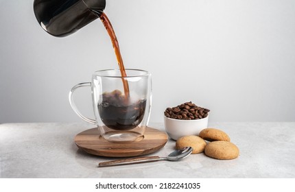 Close up professional barista pouring freshly brewed drip coffee in a glass mug. Preparing coffee alternative method. With biscuits and fresh coffee beans. - Powered by Shutterstock