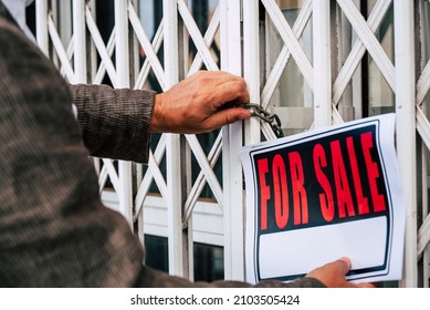 Close up of professional business man putting for sale box panel on the closed door of a store  concept of selling and buying properties and economy crisis - seller or owner close his activity 