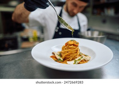 Close up of professional cook pouring sauce while serving pasta on plate. - Powered by Shutterstock