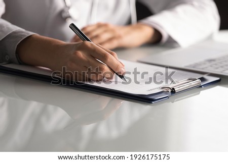 Close up professional female doctor wearing uniform taking notes in journal, physician therapist practitioner filling medical documents, clipboard, patient form, illness history, prescription
