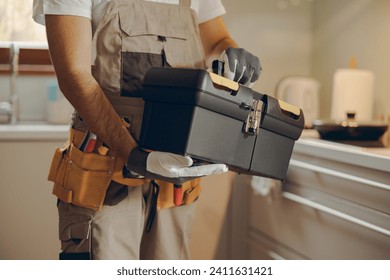 Close up of professional handyman standing on home kitchen and holding his tool bag - Powered by Shutterstock