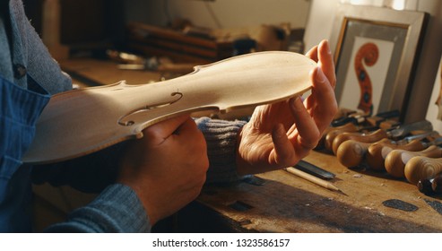 Close up of professional master artisan luthier working on creation of handmade violin  in a workshop. 