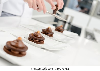 Close Up Of Professional Pastry Cook Hands Preparing Chocolate Dessert In Restaurant Kitchen