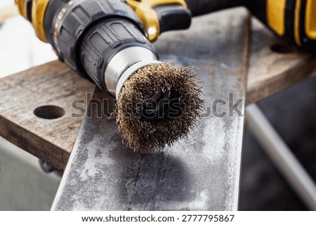 Close up of professional power tool removing rust from steel plate. Concept of metal restoration maintenance and industrial surface preparation with rotary abrasive wire brush attachment