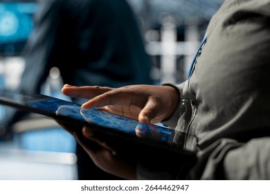 Close up of IT professional in server farm using neural networks tech on tablet, automating system diagnostic. Data center engineer using device to configure infrastructure for AI tasks