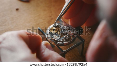 Close up of a professional watchmaker repairer working on a luxury mechanism watch gears in a workshop. 