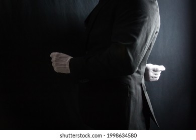 Close Up Profile Image Of Butler In Dark Suit And White Gloves Standing At Attention On Black Background. Professional Hospitality And Service.