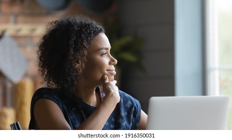 Close up profile satisfied African American woman lost in thoughts, looking to aside, visualizing future, dreaming about new opportunities, pondering strategy, distracted from laptop and online work