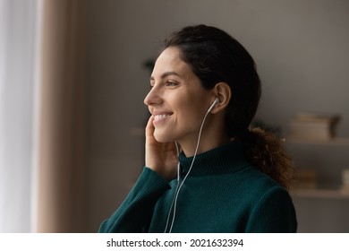 Close up profile of smiling dreamy woman listening to music, looking to aside, enjoying leisure time, favorite song, attractive young female dreaming about new opportunities, visualizing good future - Shutterstock ID 2021632394
