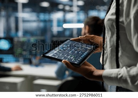 Close up of programmer in data center using tablet, managing AI training datasets. IT employee using device to oversee machine learning in server farm supporting scalable infrastructure for AI apps