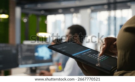 Close up of programmer utilizing AI on tablet to optimize performance and forecast issues. System administrator in office training machine learning models using device, camera A