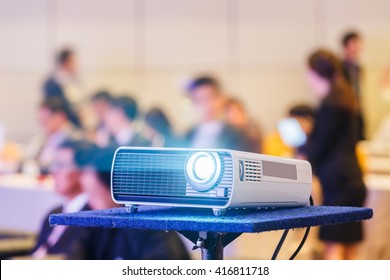 Close up projector in conference room with blurry people background