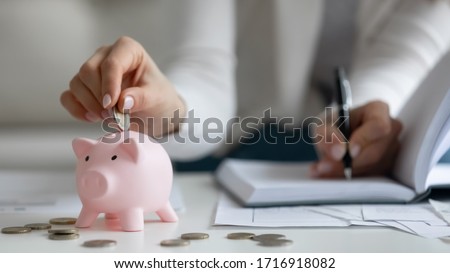 Close up of provident woman calculate household expenses put coin into piggy bank saving money for future, practical economical female manage home finances, note paying bills, investment concept