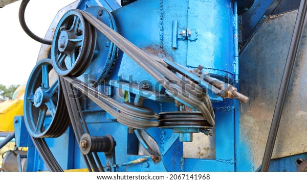 Close up pulley and belt. Transmission belt with\
multiple pulleys on a blue combine harvester background. select\
focus on subject