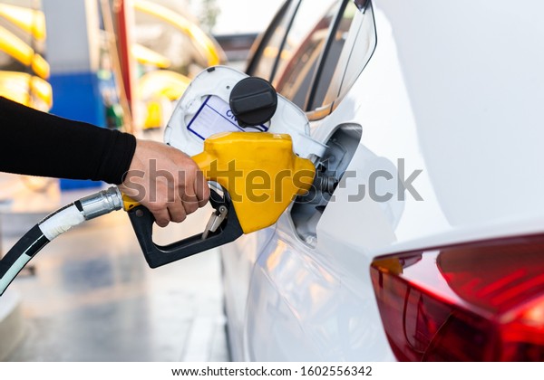 Close Up pumping gasoline fuel nozzle in tank\
for car at gas station.