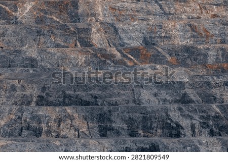 Close up quarry wall texture background with layered rock strata for industrial construction design and geological surface study wallpaper.