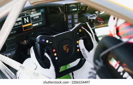 Close Up Of Race Car Driver Cockpit, Hands On Steering Wheel With Porsche Logo. Italy, September 17-18 2022, Racing Weekend