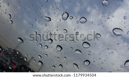 Close up - rain drops collected on the window with dark clouds in the background, Dubai, United Arab Emirates