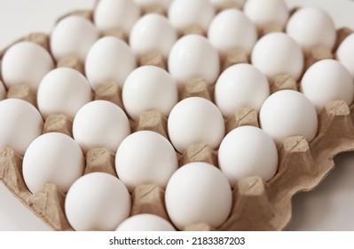 Close Up Of Raw Chicken Eggs In Paper Egg Tray On White Background. Group Of Fresh White Eggs In A Cardboard Cassette. Organic Food From Nature Good For Health