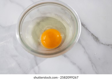 Close up of a raw egg in ramekin broken and waiting to be used for cooking