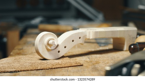 Close up of raw violin with different violin maker work tools on workbench in a workshop of professional master artisan luthier. 