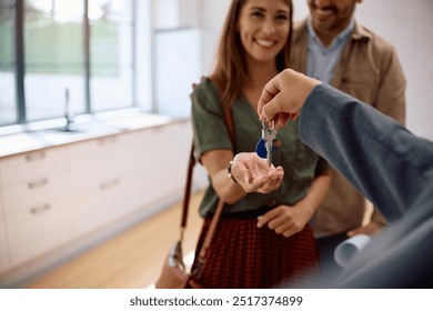 Close up of real estate agent handing over keys to a new home to a couple. - Powered by Shutterstock