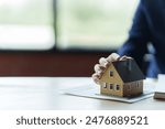 Close up real estate agent holding small house model, Home loan.