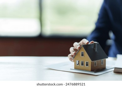 Close up real estate agent holding small house model, Home loan. - Powered by Shutterstock