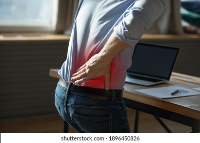 Close Up Rear View Stressed Young Man Touching Lower Back Feeling Discomfort, Suffering From Sudden Pain Due To Sedentary Lifestyle Or Long Computer Overwork In Incorrect Posture At Home Office.