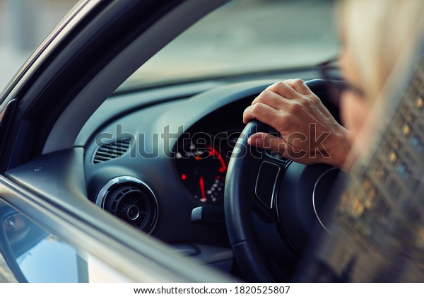 Close up rear view of a woman driving car through\
the city