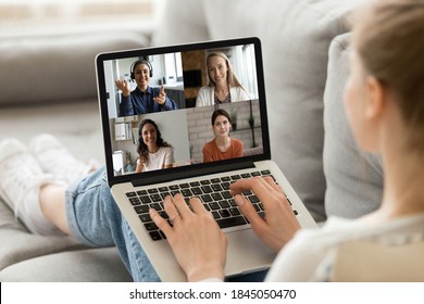 Close up rear view woman engaged in virtual conference with diverse colleagues, sitting on couch, businesswoman talking with colleagues by video call, internet negotiations, brainstorming from home